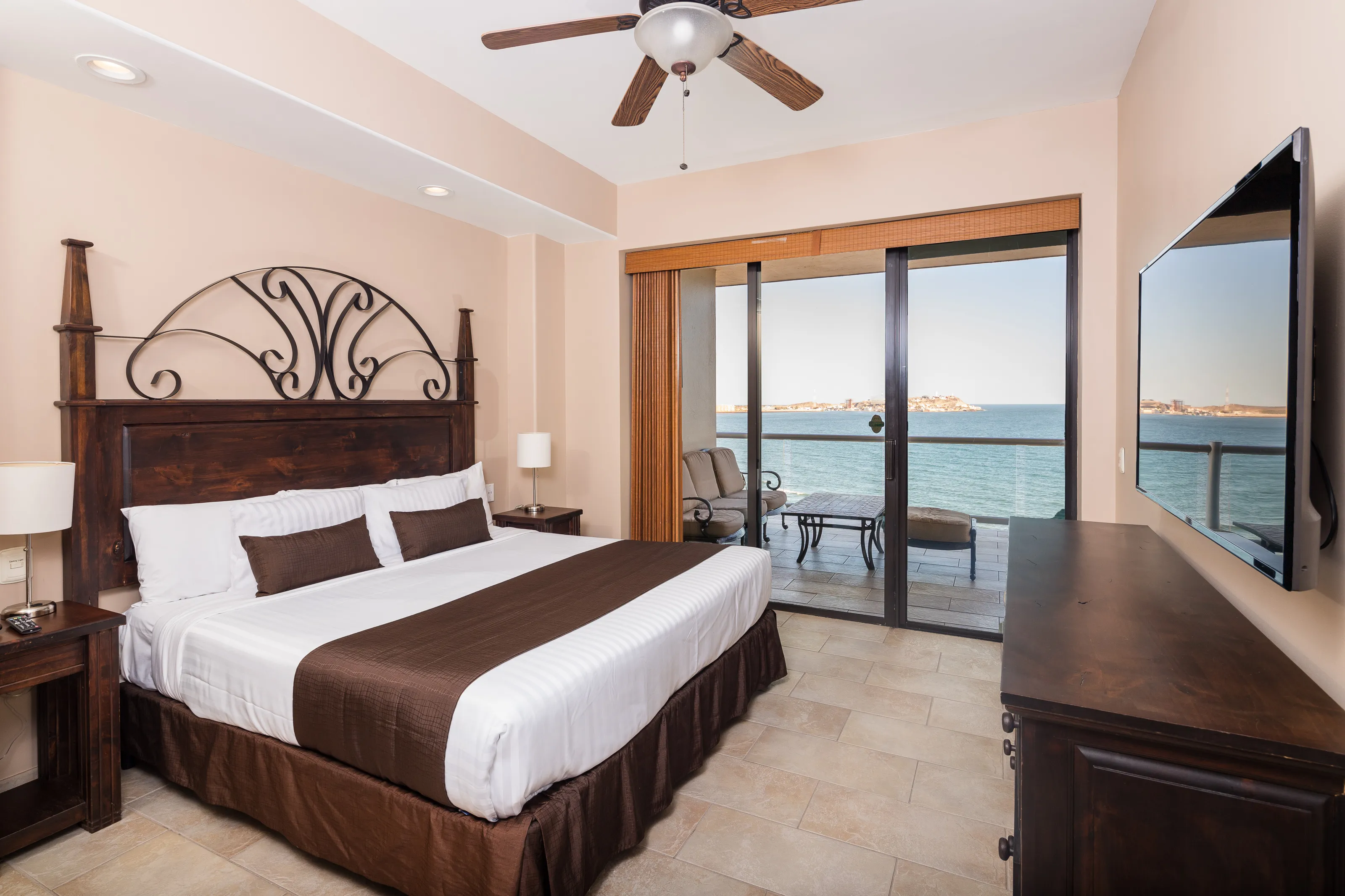 Cozy hotel room with a king-sized bed and ocean view balcony.