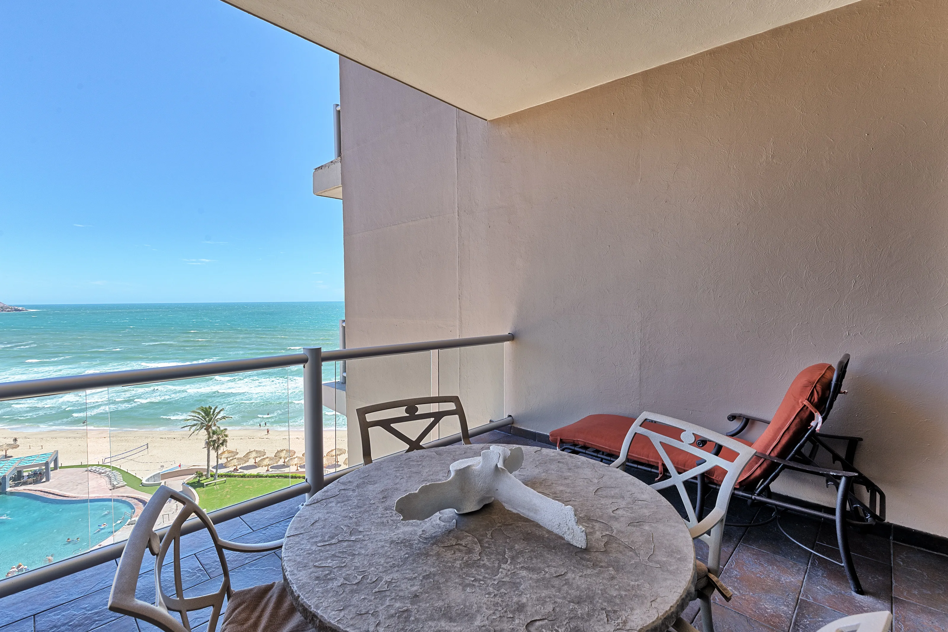 Cozy balcony overlooking the ocean with a round table and chairs.