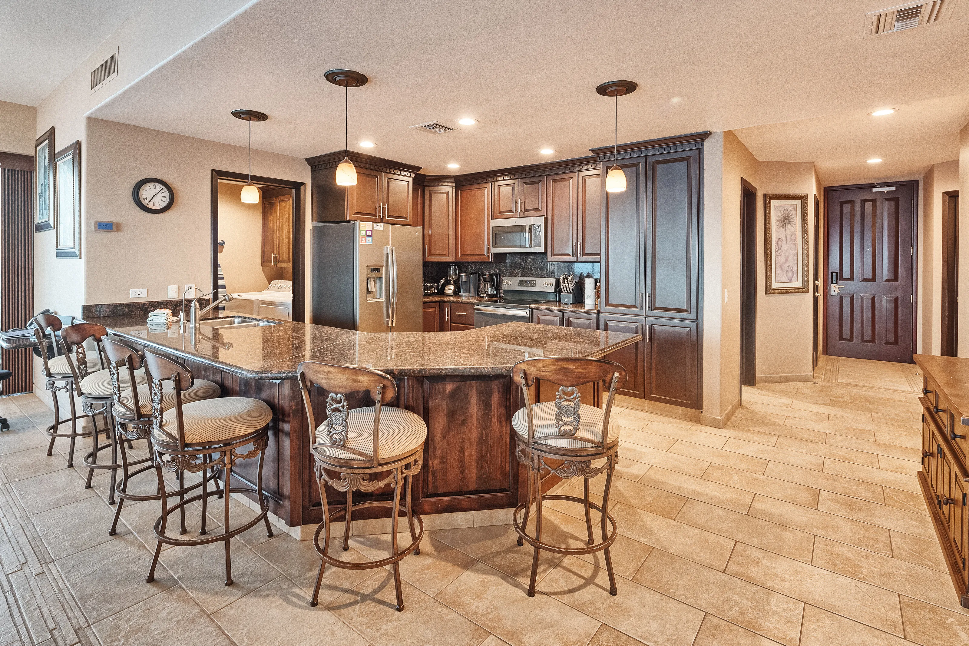 Spacious kitchen with wooden cabinets and a large island with bar stools.