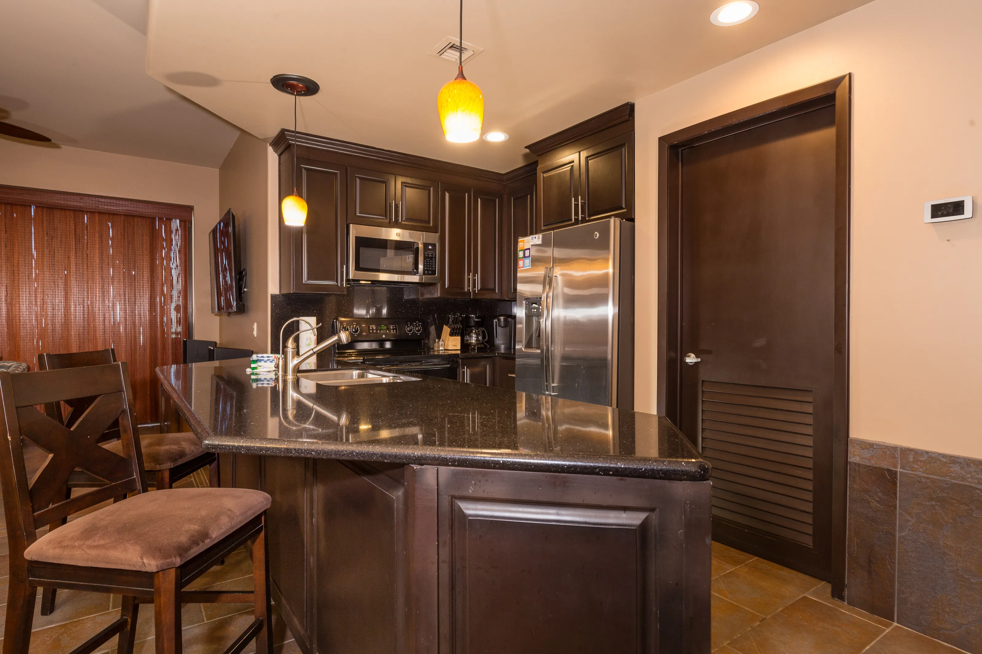 Modern kitchen with dark wood cabinets and stainless steel appliances.