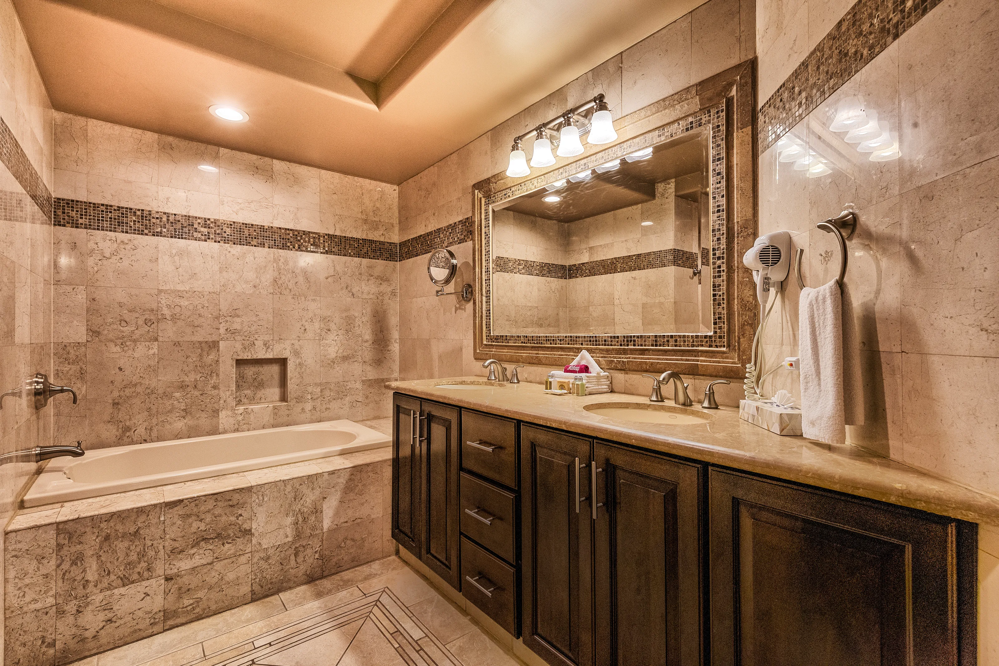 Elegant bathroom with marble tiles and a large mirror above a dark wood vanity.